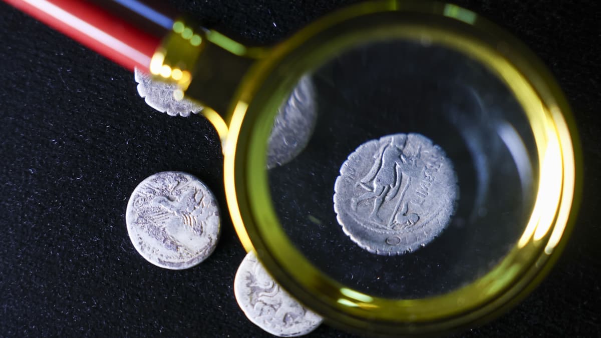 Eine Numismatikerin (Münzforscherin)  untersucht eine über 2000 Jahre alte Silbermünze mit dem Abbild des heimkehrenden Odysseus mit Wanderstab, der von seinem Hund Argos begrüßt wird, im Landesmuseum für Vorgeschichte. Bei einem außergewöhnlichen Hortfund wurden erstmals in Sachsen-Anhalt fünf dieser Silberdenare der Römischen Republik entdeckt. Unter der Lupe sieht man: Die uralte Silbermünze zeigt einen Mann und einen Hund..<span class='image-autor'>Jan Woitas/dpa</span>